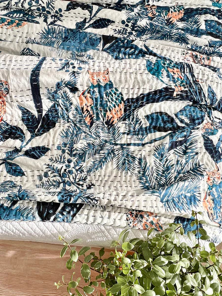 Floral-patterned quilt on a bed with a plant in the foreground