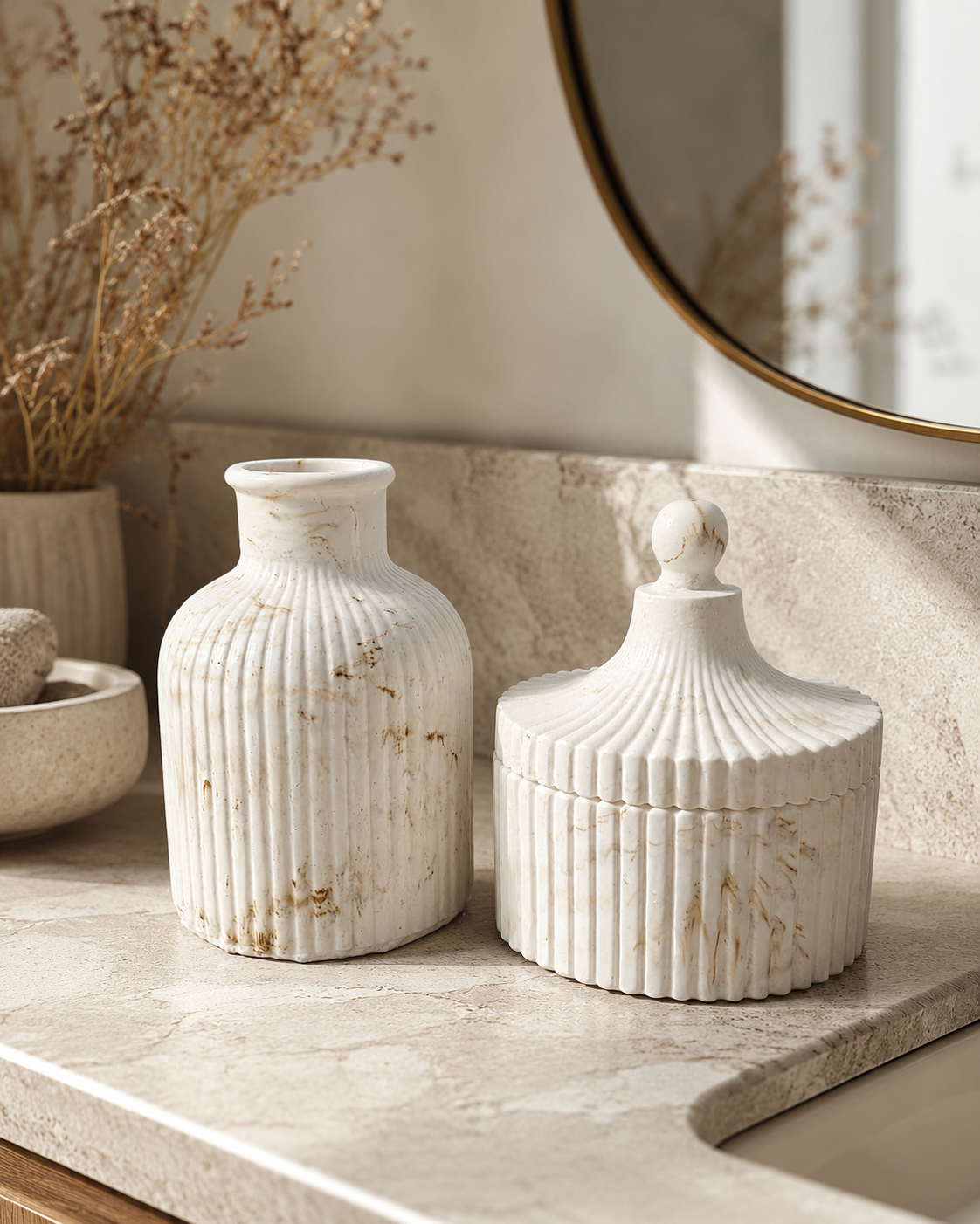 Two ribbed ceramic vases in an off-white marble finish with subtle gold veining, displayed on a stone countertop in a bathroom setting.