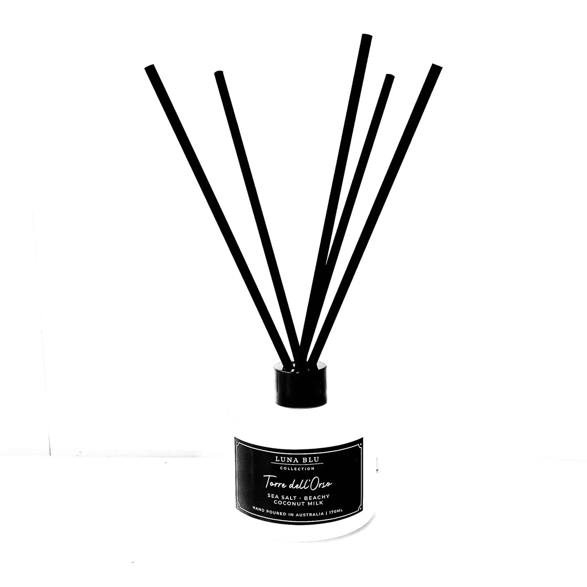 A reed diffuser bottle with a white glass container, a black cap, and six black reeds, featuring a black label with white text that reads 'LUNA RUI' and 'Terra del Suelo'.