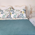 Bed with teal bedding and floral-patterned pillows in a bedroom setting.