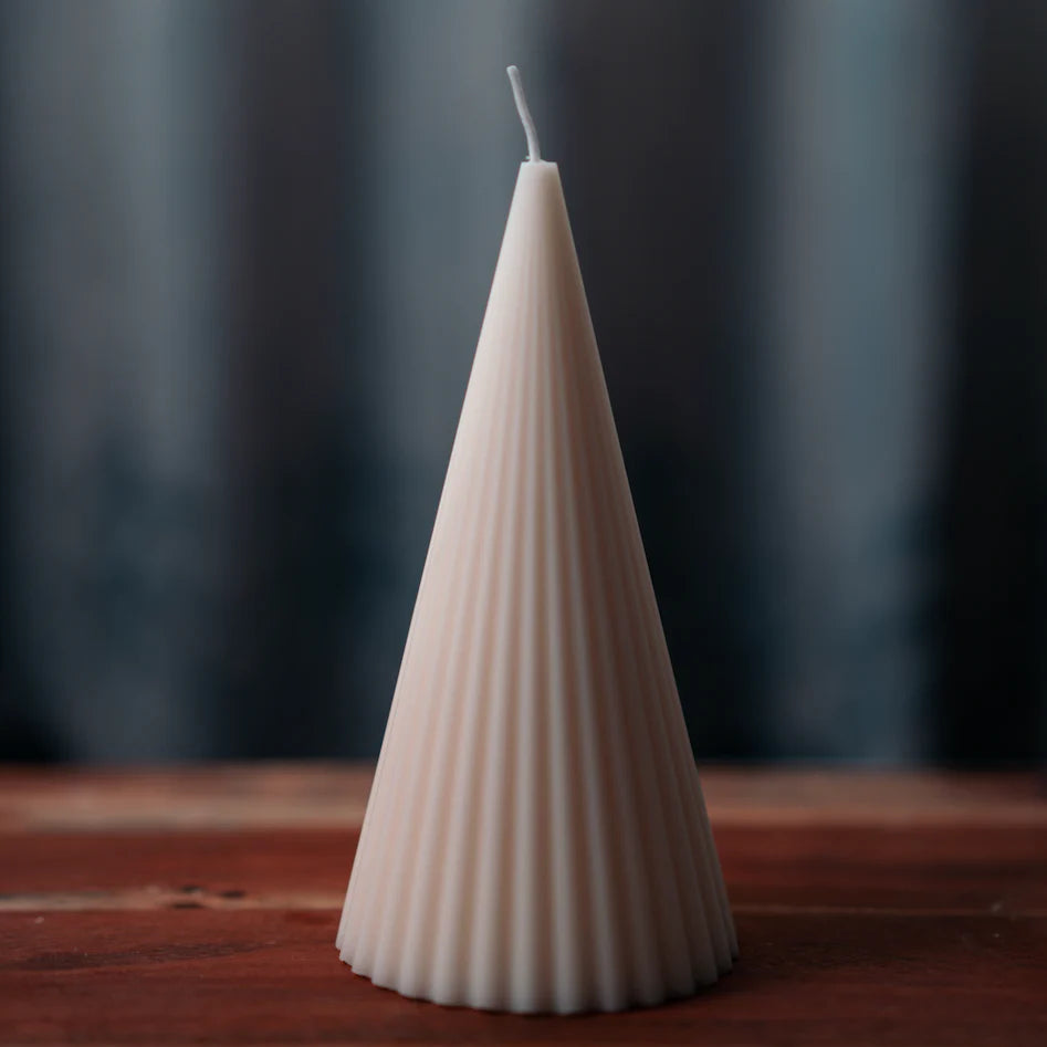 Conical candle with ribbed texture on a wooden surface