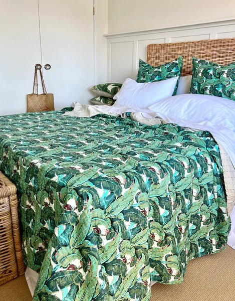 Bed with green leaf-patterned bedding in a bedroom setting.