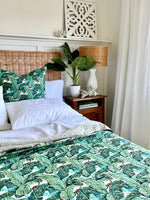 Bedroom with green leaf-patterned bedding, wicker headboard, and decorative elements.