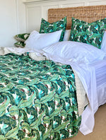 Bed with green leaf-patterned comforter and pillows in a bedroom setting