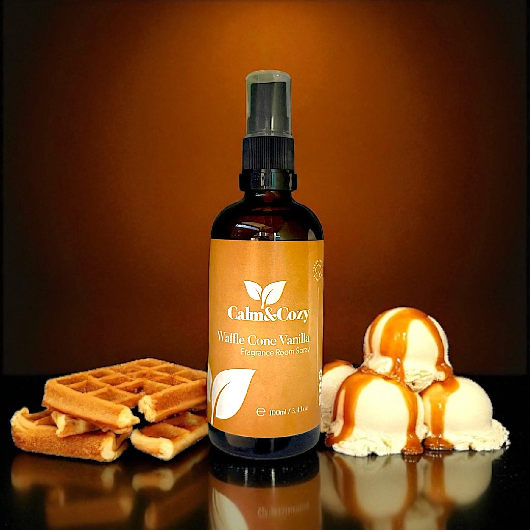 Bottle of Calm & Cozy Waffle Cone Vanilla spray with waffles and ice cream on a reflective surface.