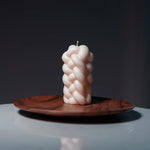 Braided candle on a wooden plate with a dark background