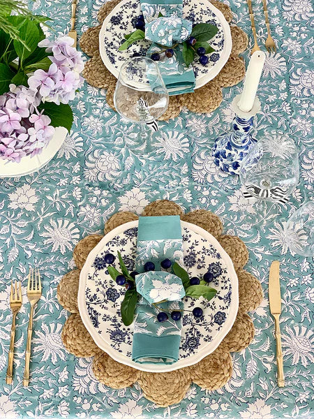 Table setting with floral tablecloth, plates, cutlery, and decorative elements.