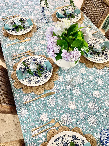 Elegant table setting with floral tablecloth, plates, and flowers.