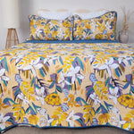 Floral and bird patterned bedspread on a bed with matching pillows.