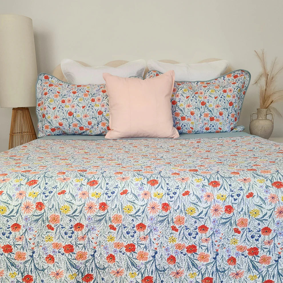 Floral patterned bedspread on a bed with pillows in a bedroom setting.