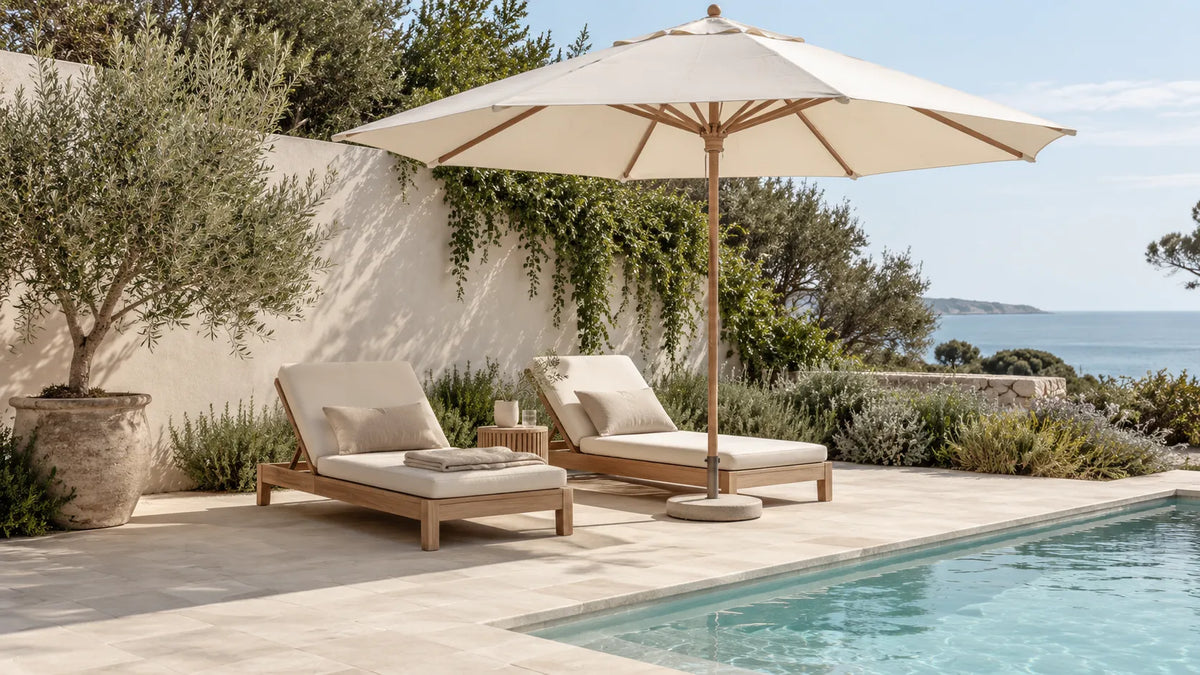 A cream outdoor umbrella shading timber loungers beside a pool