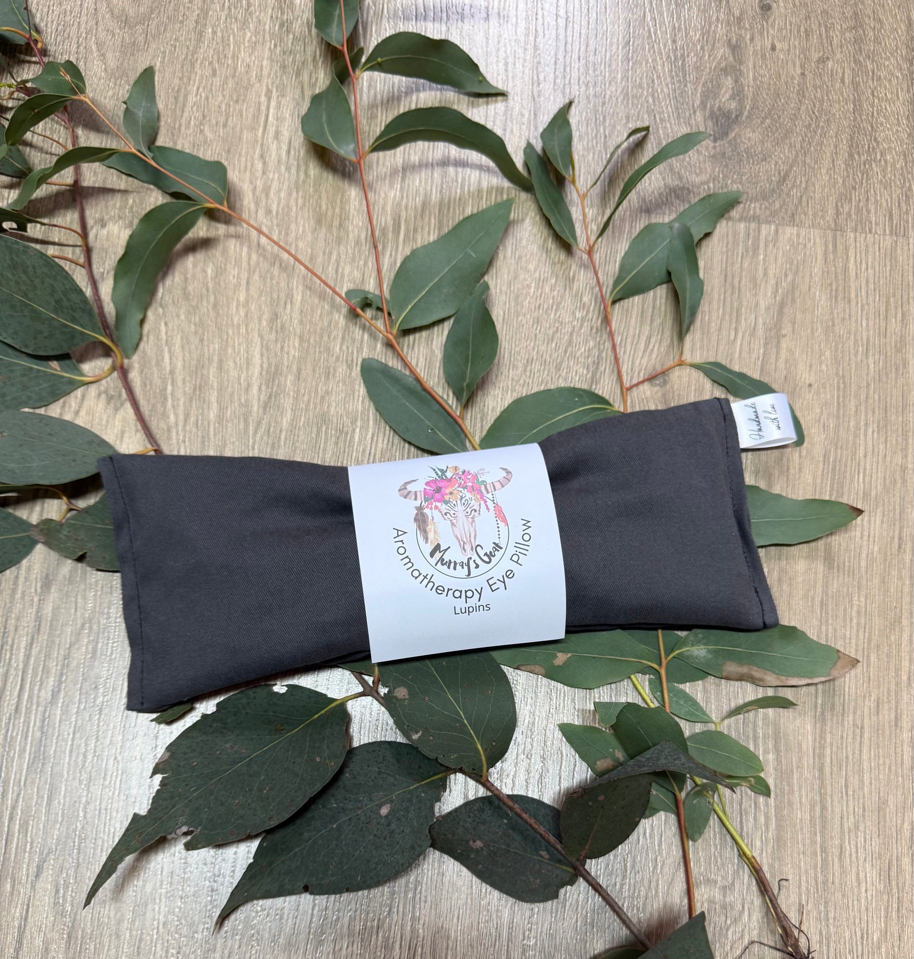 Charcoal eye pillow with a label on a wooden surface with eucalyptus leaves
