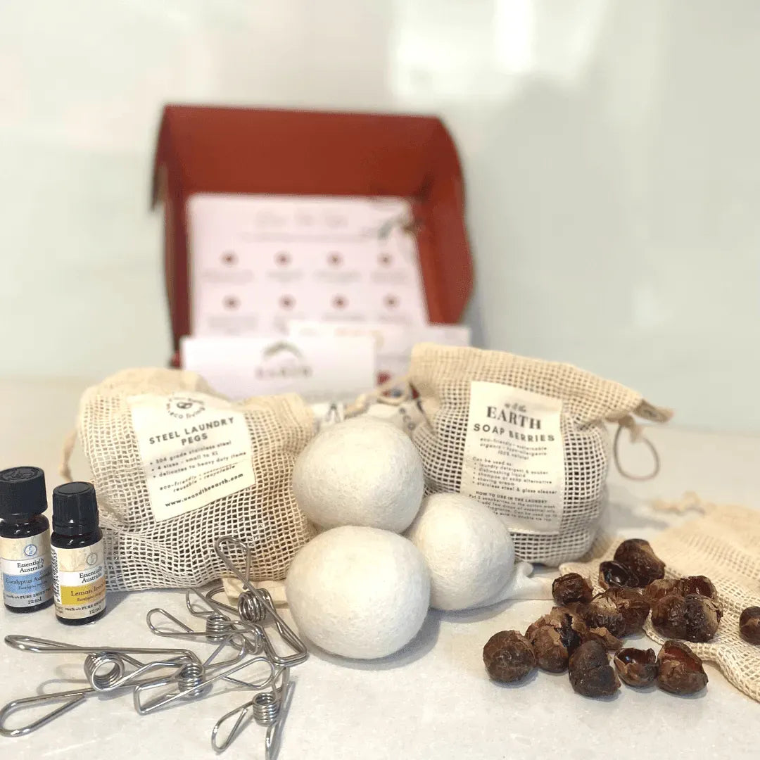 Set of natural laundry products including balls, soap bars, and essential oils on a white surface.
