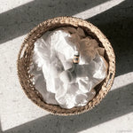 Woven basket with white fabric and a small decorative item on a concrete surface