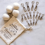 Set of natural laundry balls, clips, and a drawstring bag labeled 'Out of the Earth' on a marble surface.
