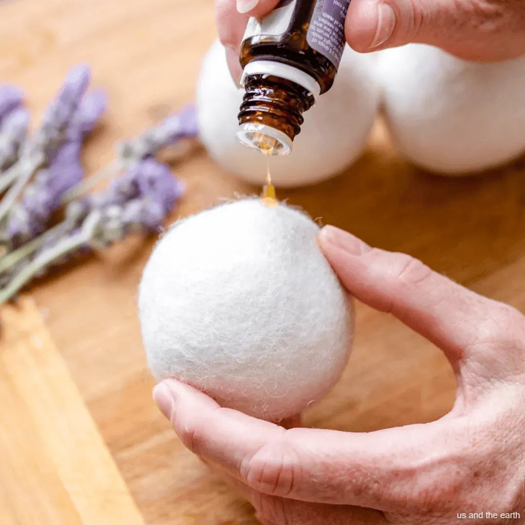 Person adding essential oil to a bath bomb with lavender flowers in the background