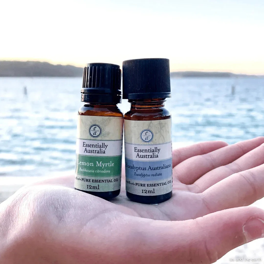 Two essential oil bottles held in a hand with a blurred natural background