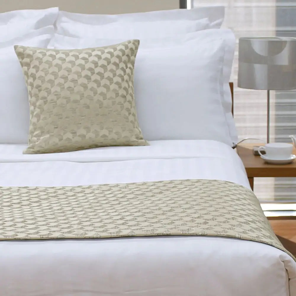 Neatly made bed featuring Jason Regency Champagne Square Cushion on white linens