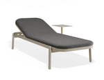 A modern outdoor chaise lounge chair with a dark gray cushioned seat and a light beige metal frame, featuring an integrated side table, shown on a white background.