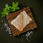 Wooden spoon on a woven mat with salt and mint leaves on a dark background